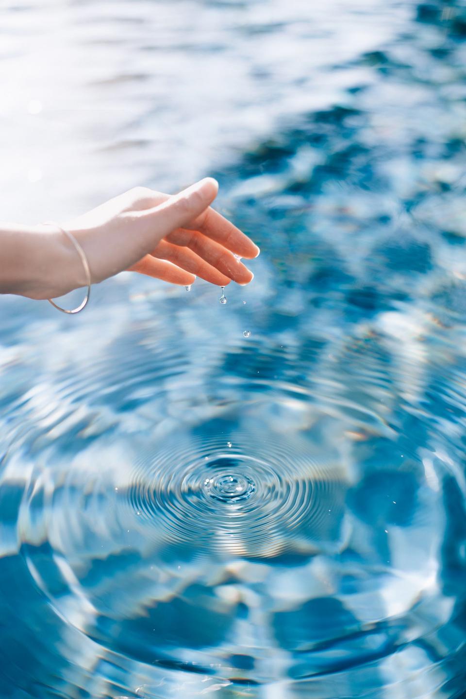 A hand held above clear rippling water