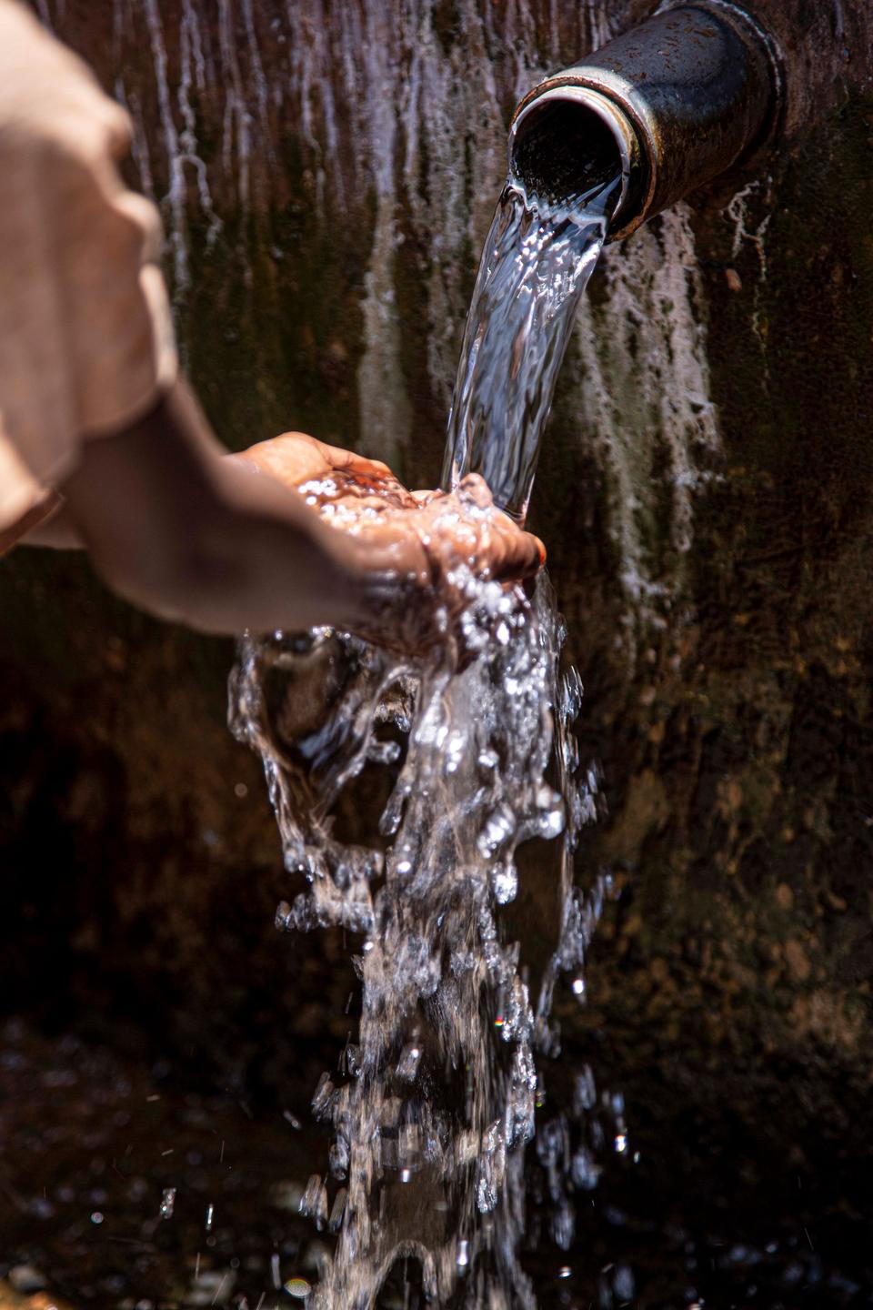 Hands cupped under running spring water